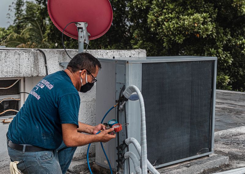 HVAC technician servicing a condenser unit with gauges
